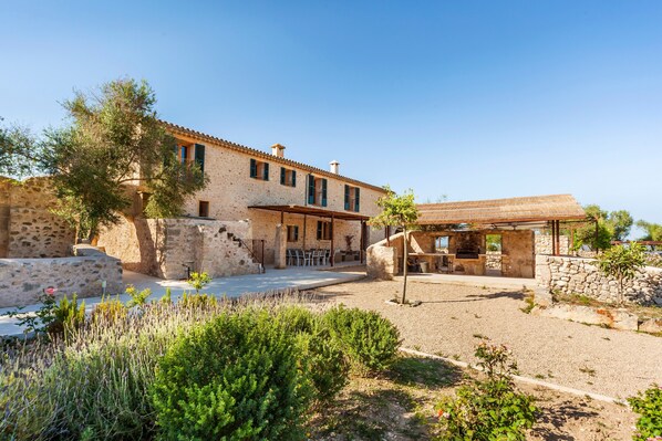 A stone building with a patio area, outdoor seating, and a view of the sea.