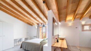 Une chambre à coucher moderne avec un lit, un bureau, une coiffeuse et un grand miroir.