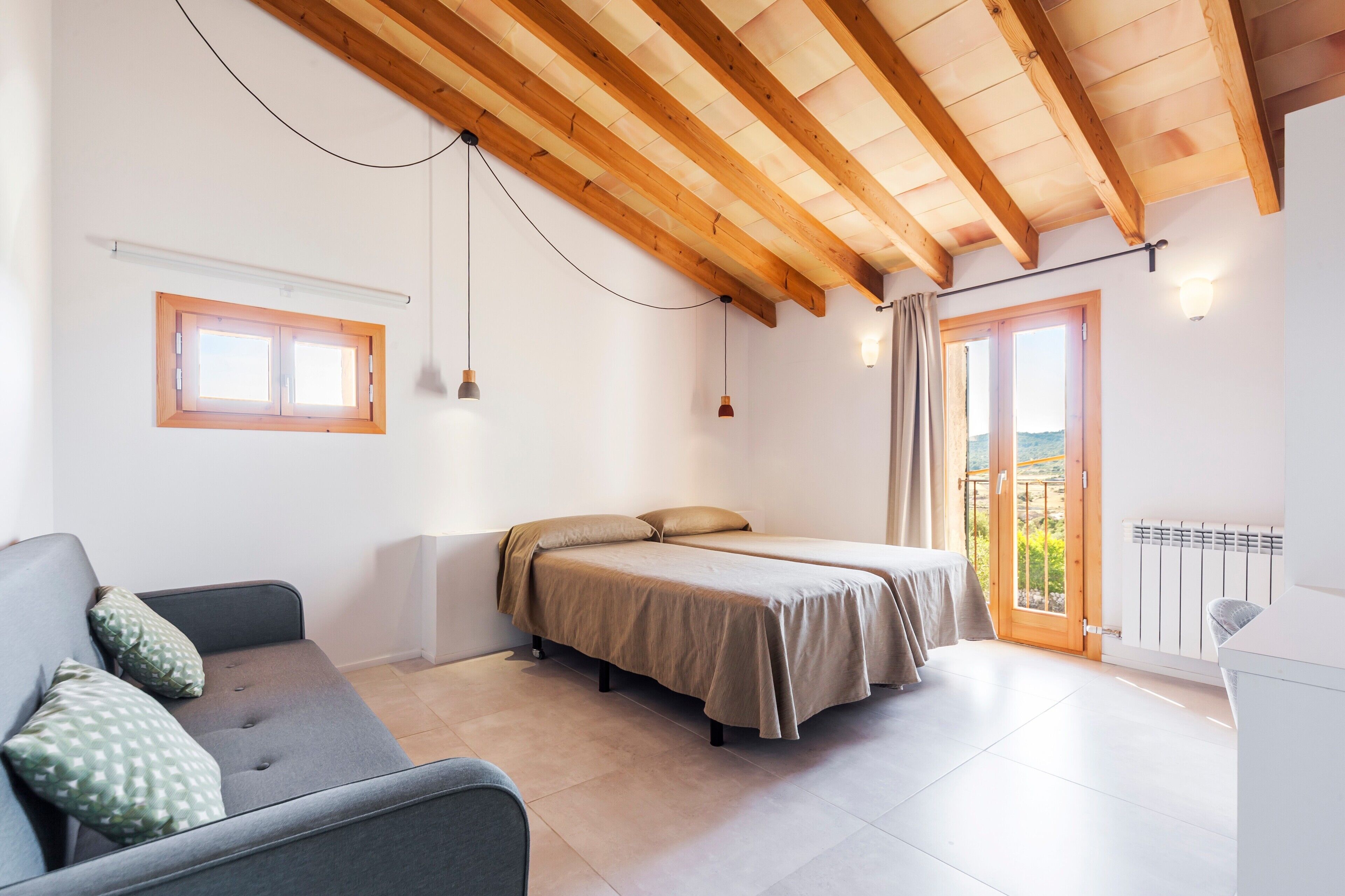 A room with a bed, a sofa, a window, and a balcony.