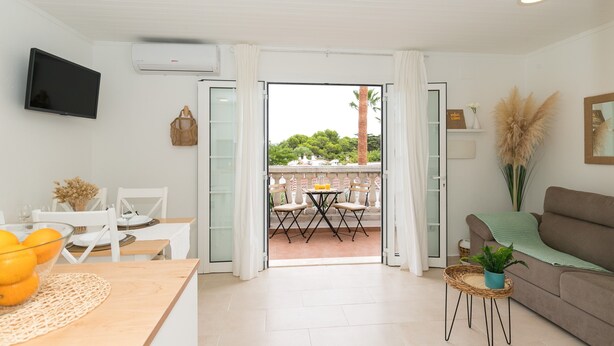 Een moderne woonkamer met een eetgedeelte, een bank, een televisie en een balkon met uitzicht.