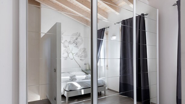 Un dormitorio moderno con cama, mesita de noche, luz de pared y ventana con cortinas.
