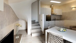 Una cocina moderna con una escalera, un comedor con mesa y sillas, y un televisor a la izquierda.