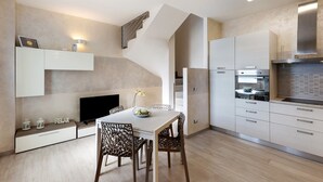 Una cocina moderna con comedor, electrodomésticos integrados y una escalera.