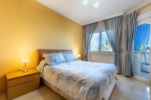 A bedroom with a bed, nightstand, lamp, curtains, and a window with a view. - Beautiful Apartment Costa Lago on the Beach with Pool, Wi-Fi & Sea View; Parking Available (Torremolinos)