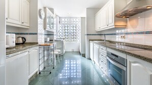 A kitchen with white cabinets, a stainless steel range hood, a dishwasher, and a window with a decorative grid. - Beautiful Apartment Costa Lago on the Beach with Pool, Wi-Fi & Sea View; Parking Available (Torremolinos)