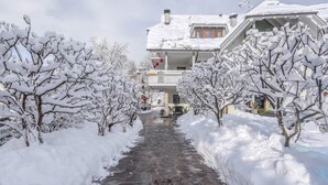 A snow-covered pathway leading to a building with balconies and a snow-covered roof. - Charming Apartment "Sahara" in Villa Anina with Pool (Klobenstein Ritten)