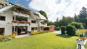 Een gebouw met twee verdiepingen, een balkon, een zwembad en een verzorgd gazon.