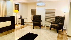 Un salon moderne comprenant un comptoir d’accueil, deux fauteuils, une table basse et un tapis noir.