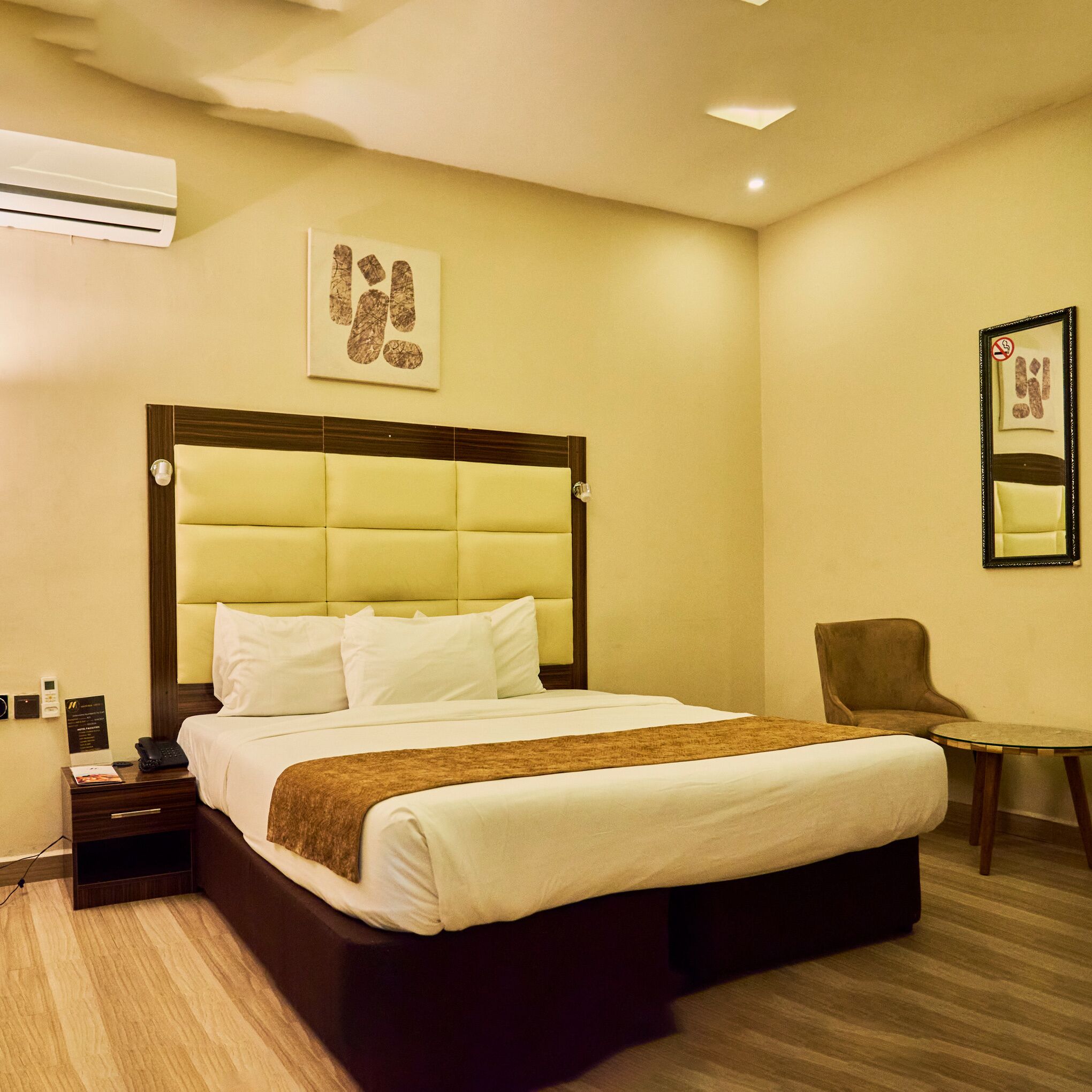 Una habitación de hotel con una cama grande, una mesita de noche con un teléfono, una silla y una pequeña mesa.
