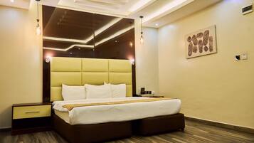 Habitación de hotel moderna con una cama grande, suelo de madera y un diseño de techo contemporáneo.