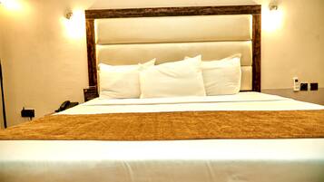 A neatly made bed with white linens and a brown throw blanket.