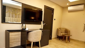 Une chambre d’hôtel moderne équipée d’un bureau, d’une chaise et d’une petite table ronde.