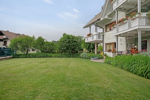 Un bâtiment à deux étages doté d’un balcon, d’une pelouse bien entretenue et entouré de verdure.