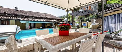 Un espacio al aire libre cubierto con piscina, muebles de mimbre y una maceta roja.