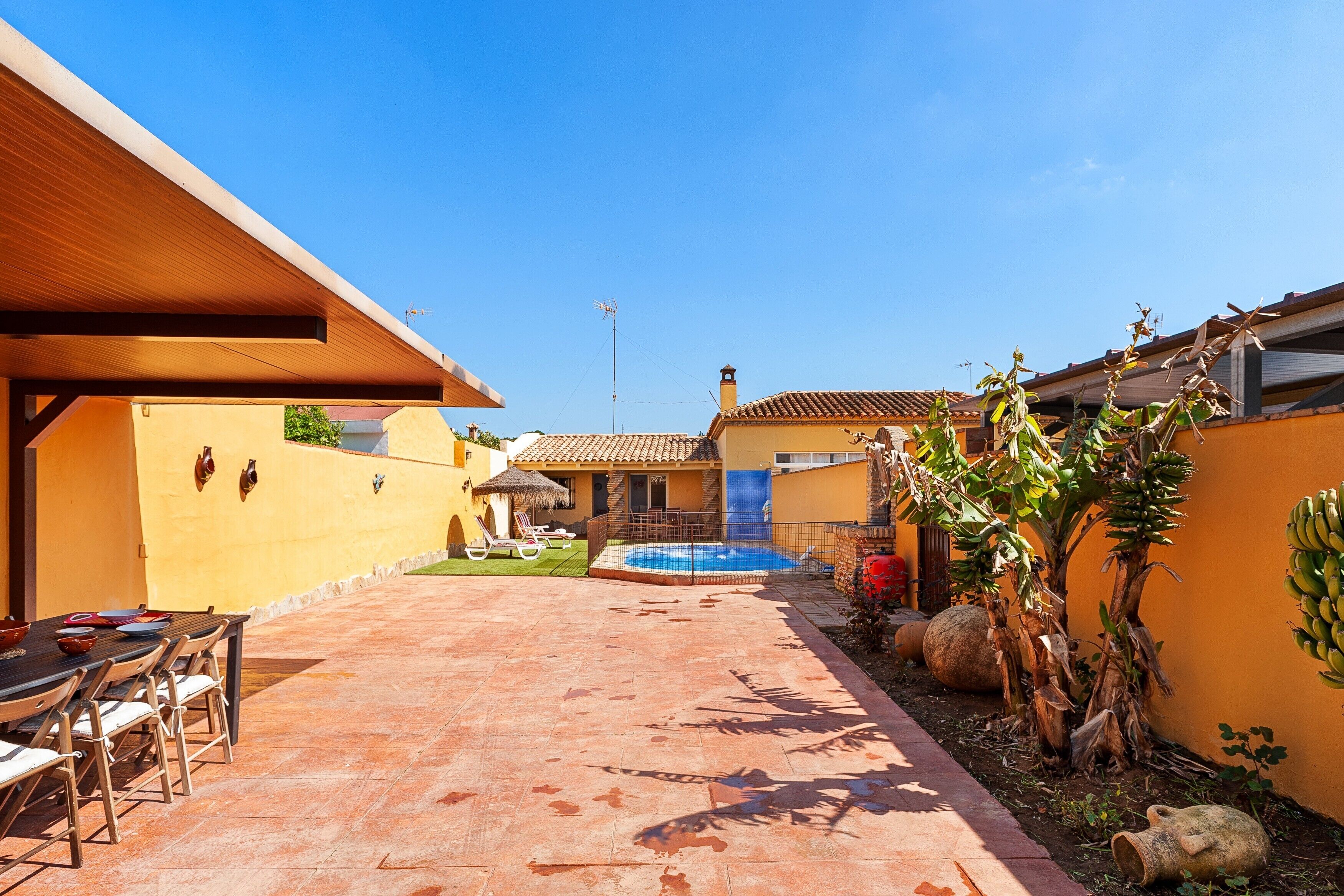 A courtyard with a pool, outdoor seating, and a covered area.