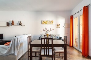 Zona de dinar amb taula, cadires i un ram de flors.