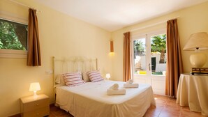 Une chambre d’hôtel avec un lit, une table de chevet, une lampe, une table avec une lampe et une vue sur l’extérieur.