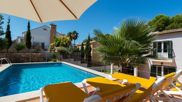 Une piscine avec des chaises longues jaunes et un parasol.