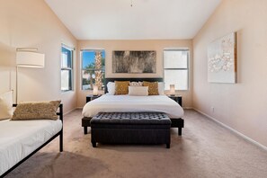 A bedroom with a large bed, a bench, a nightstand, and a lamp.