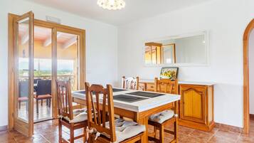 Ein Essbereich mit Tisch und Stühlen, einem Schrank, einem Spiegel und einer Glastür zum Außenbereich.