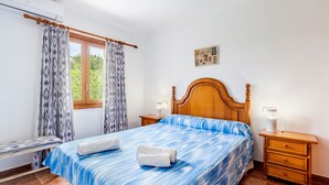 A bedroom with a bed, two bedside tables, a window with curtains, and a wall-mounted picture. - Rural Charm with Pool – Villa Damián 12 (Alcúdia)
