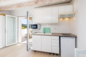 A modern kitchen with white cabinets, a microwave, a toaster, and a small refrigerator.
