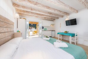 Une chambre à coucher comprenant un lit, un bureau, une chaise, un téléviseur et donnant sur l’extérieur.