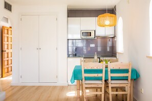 A kitchen with white cabinets, a microwave, and a hanging light fixture.