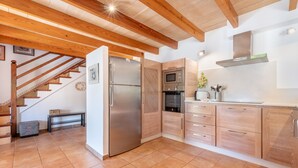 Eine Küche mit Holzausstattung, einem Edelstahlkühlschrank, einer Mikrowelle und einem Herd.