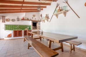 Une cuisine spacieuse avec une longue table en bois, des bancs et un mur recouvert de carreaux.