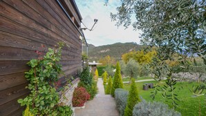 A wooden exterior wall with a stone pathway leading to a garden. - In the hills with panoramic views – Apartment GeoResort A4 (Tremosine)