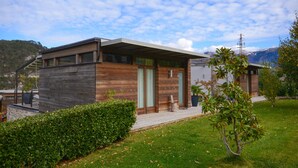 A modern house with a wooden exterior, a covered porch, and a small garden. - In the hills with panoramic views – Apartment GeoResort A4 (Tremosine)