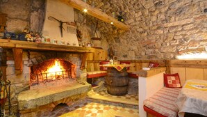 A rustic stone-walled room with a fireplace, wooden shelves, a bed, and a barrel. - In the hills with panoramic views – Apartment GeoResort A4 (Tremosine)
