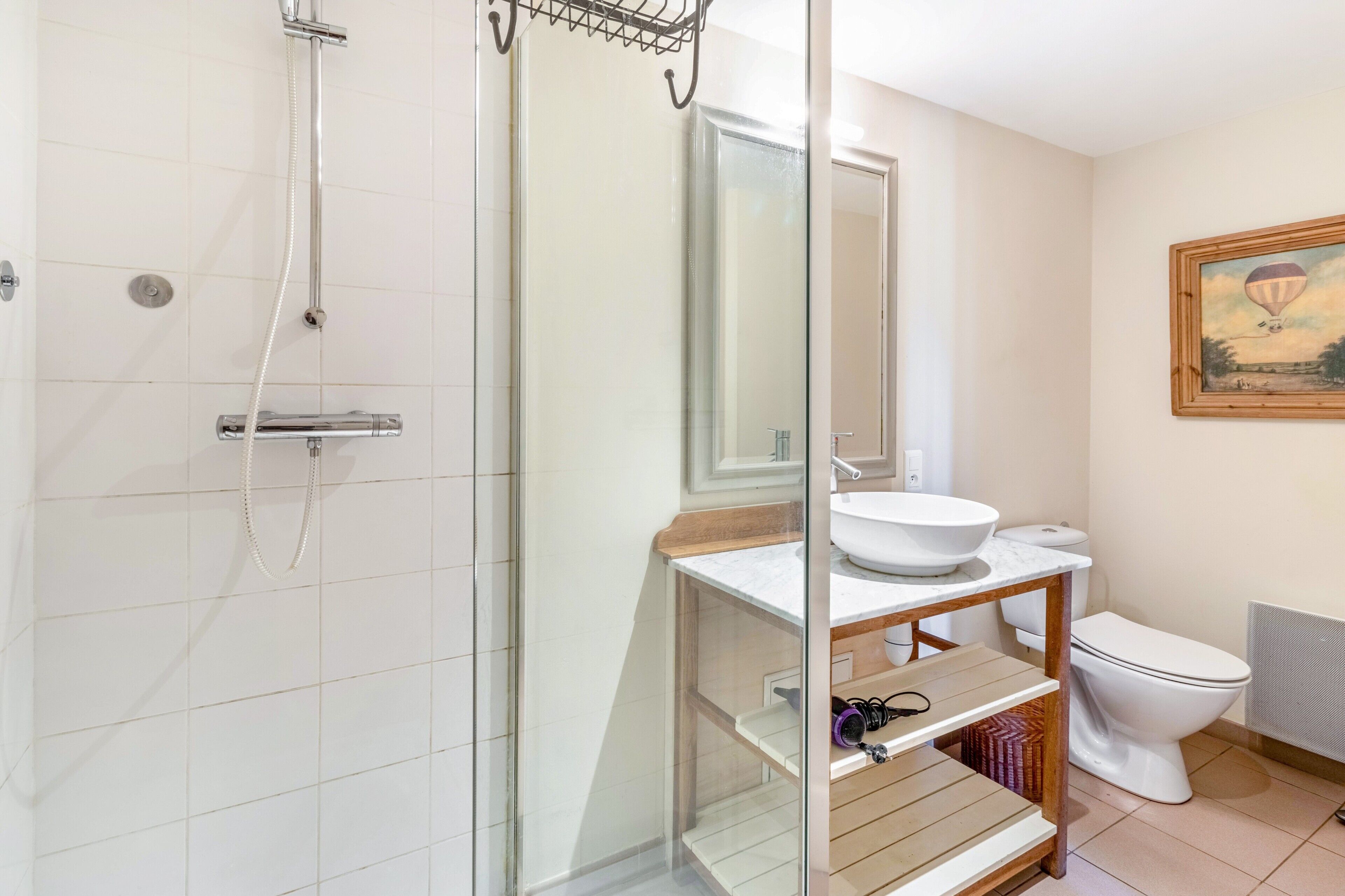 Un bagno con doccia vetrata, un lavandino bianco su mobile in legno e un water.