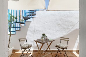 Een klein terras met een tafel, twee stoelen, een plant in pot en een blauwe balustrade.