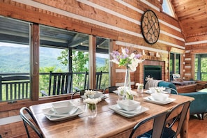 Enjoy meals with a view of the surrounding mountains from this cabin's spacious dining area, featuring a large table for four and comfortable seating.