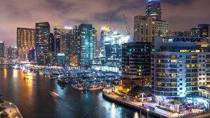 Uma marina com barcos e o horizonte urbano à noite.