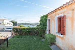 Un immobile residenziale con giardino, vista sul mare e un'auto bianca parcheggiata nel vialetto.
