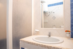 Een badkamer met een wastafel, spiegel en douche.
