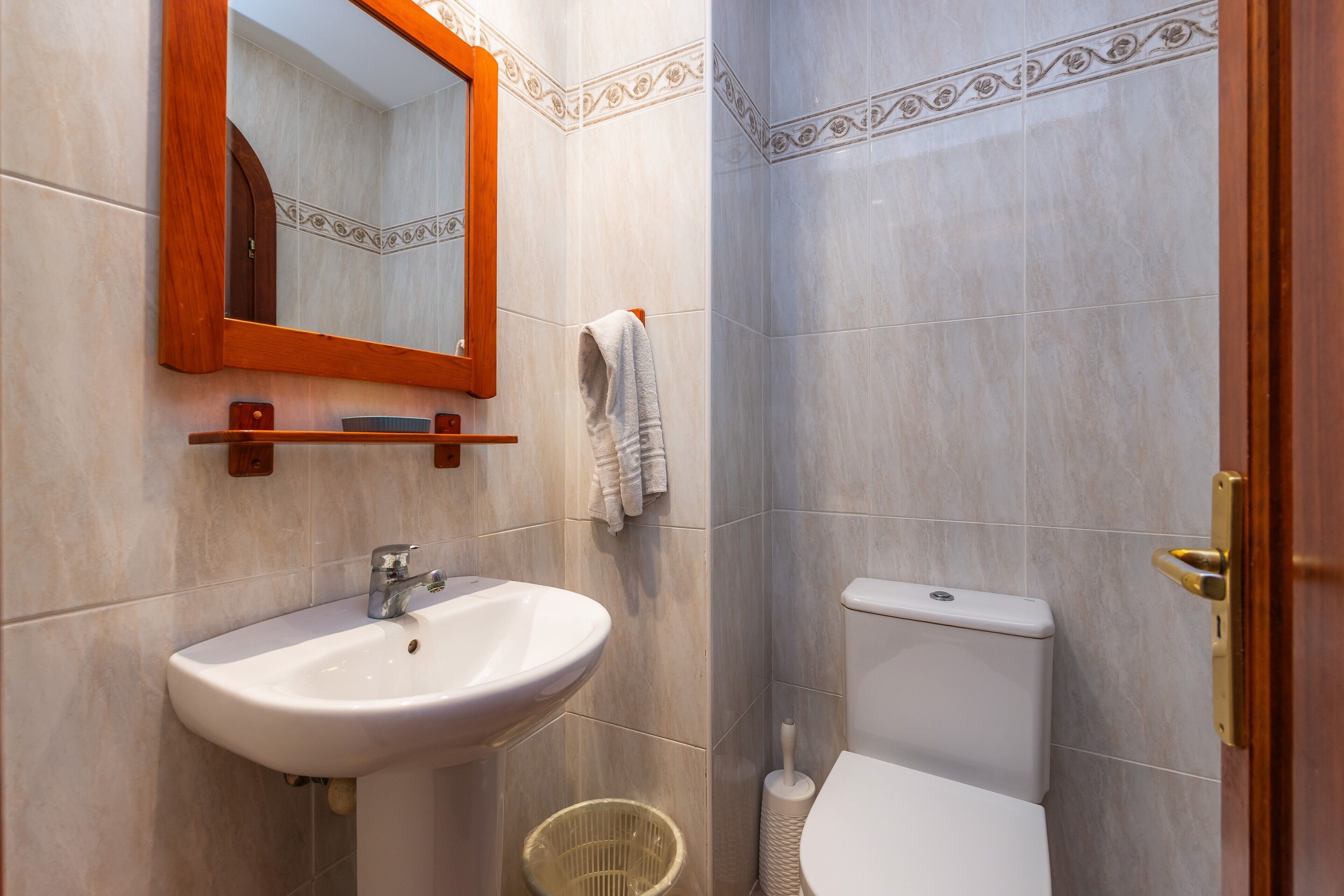 A bathroom with a sink, mirror, toilet, and a towel rack.