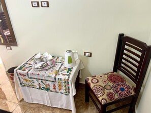 A dining table with a tablecloth featuring Egyptian hieroglyphs, a kettle, and several cups and plates. - Sphinx Palace Guest House (Giza)