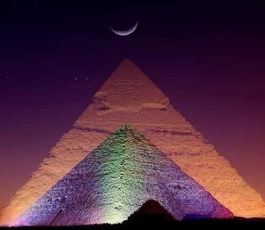 Una pirámide con un patrón de color degradado y una luna creciente en el cielo.