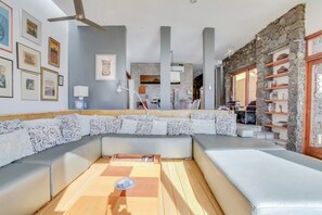 A modern living room with a sectional sofa, a wooden coffee table, and a stone wall.