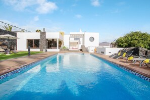 A swimming pool with a modern house in the background.