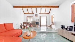 Un salon avec un canapé, une table basse et un téléviseur posé sur un meuble en bois.