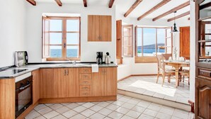 Une cuisine avec des meubles en bois, une cuisinière et une vue sur la mer.
