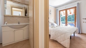 Ein Schlafzimmer mit Bett, ein Badezimmer mit Waschbecken und ein großes Fenster.