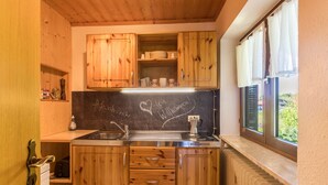 Eine Küche mit Holzausstattung, einer Tafel und einem Fenster mit Vorhängen.