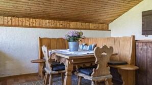 Ein Holztisch mit Stühlen, einer Topfpflanze und einem gemusterten Teppich.