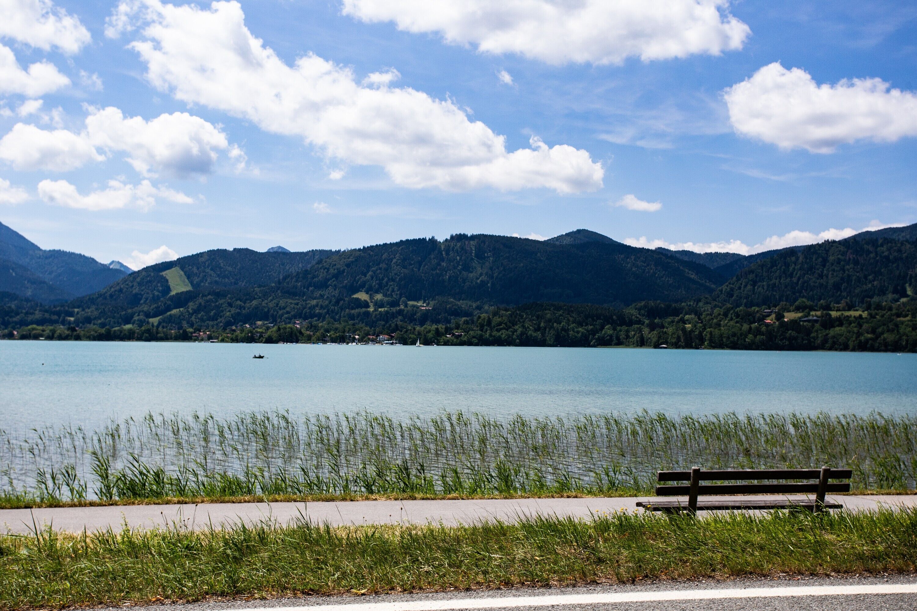 Un banc au bord d’un lac, avec des montagnes en arrière-plan.